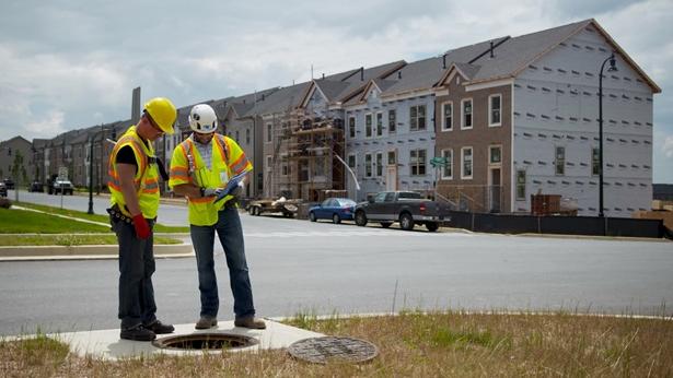 Construction workers examining a manhole
